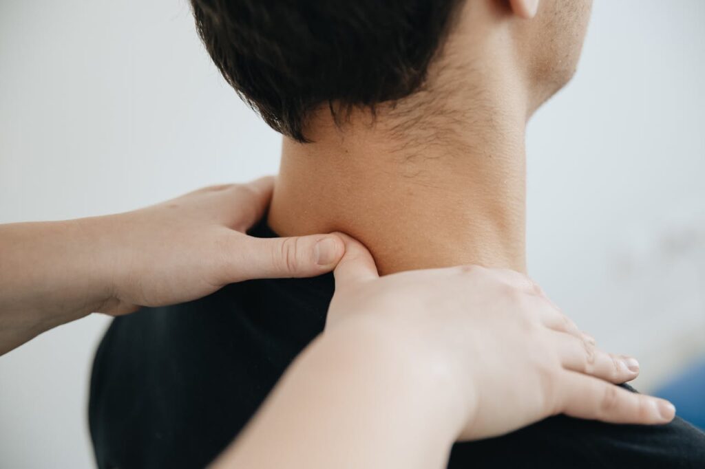 pexels-photo-20860604 Close-up of a physiotherapist providing neck massage for pain relief in a clinic setting.